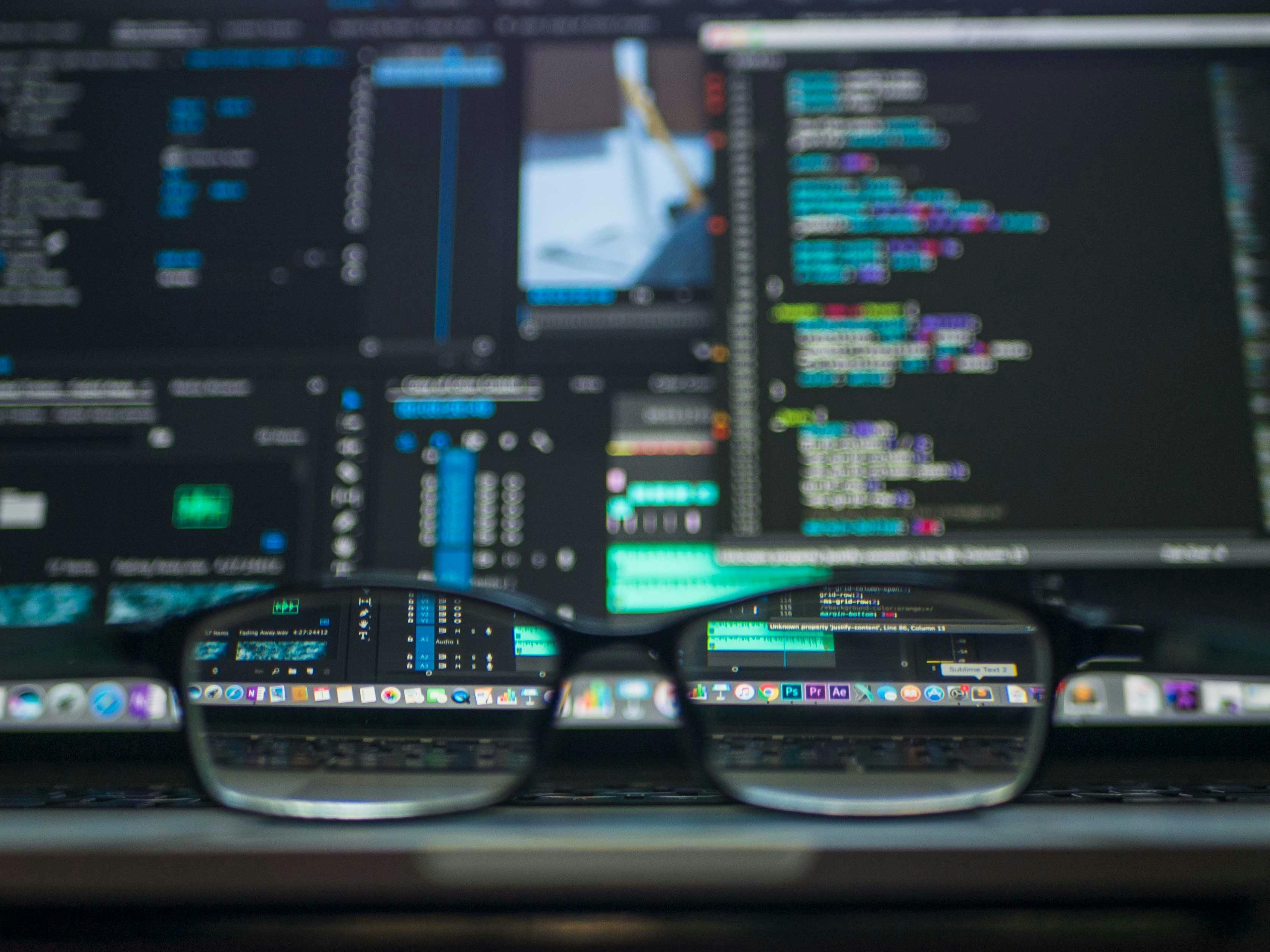 A computer displaying complex information, with a pair of glasses sitting on it